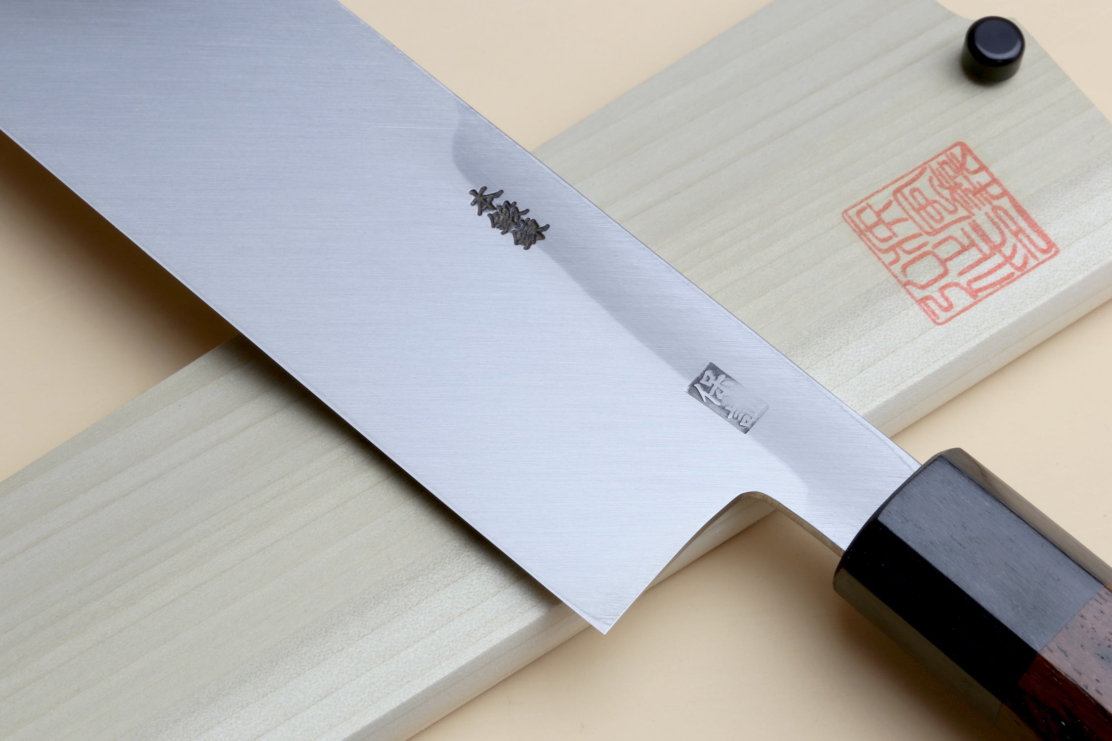 Japanese vegetable knife close-up: blue steel blade with engraved marks and rosewood handle