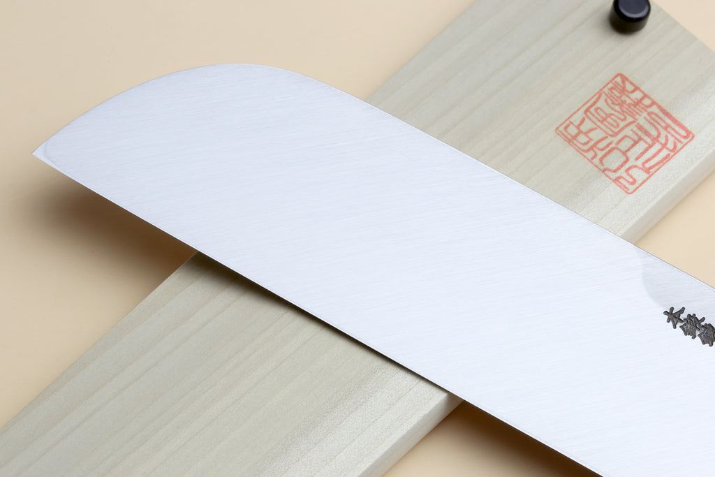 Japanese vegetable knife blade beside light wood saya and stamped maker seal