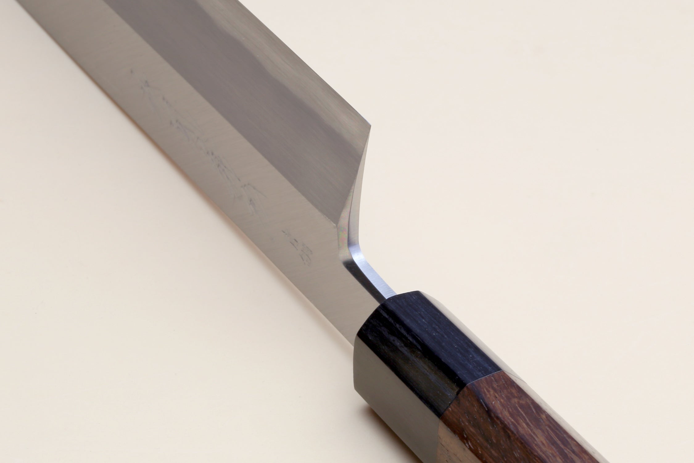 Traditional Japanese vegetable knife with blue steel blade and rosewood handle, angled close-up