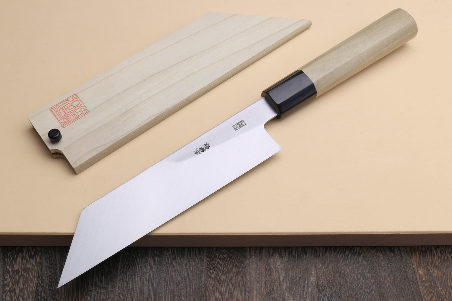 Japanese chef knife with light wooden saya and dark collar, exposed polished steel blade