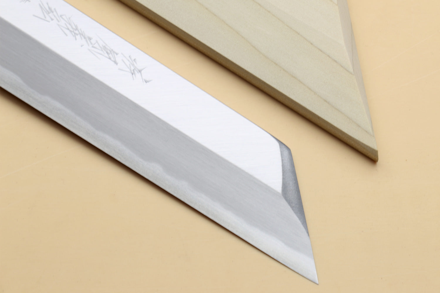 Japanese chef knife blade close-up with etched markings and pointed tip