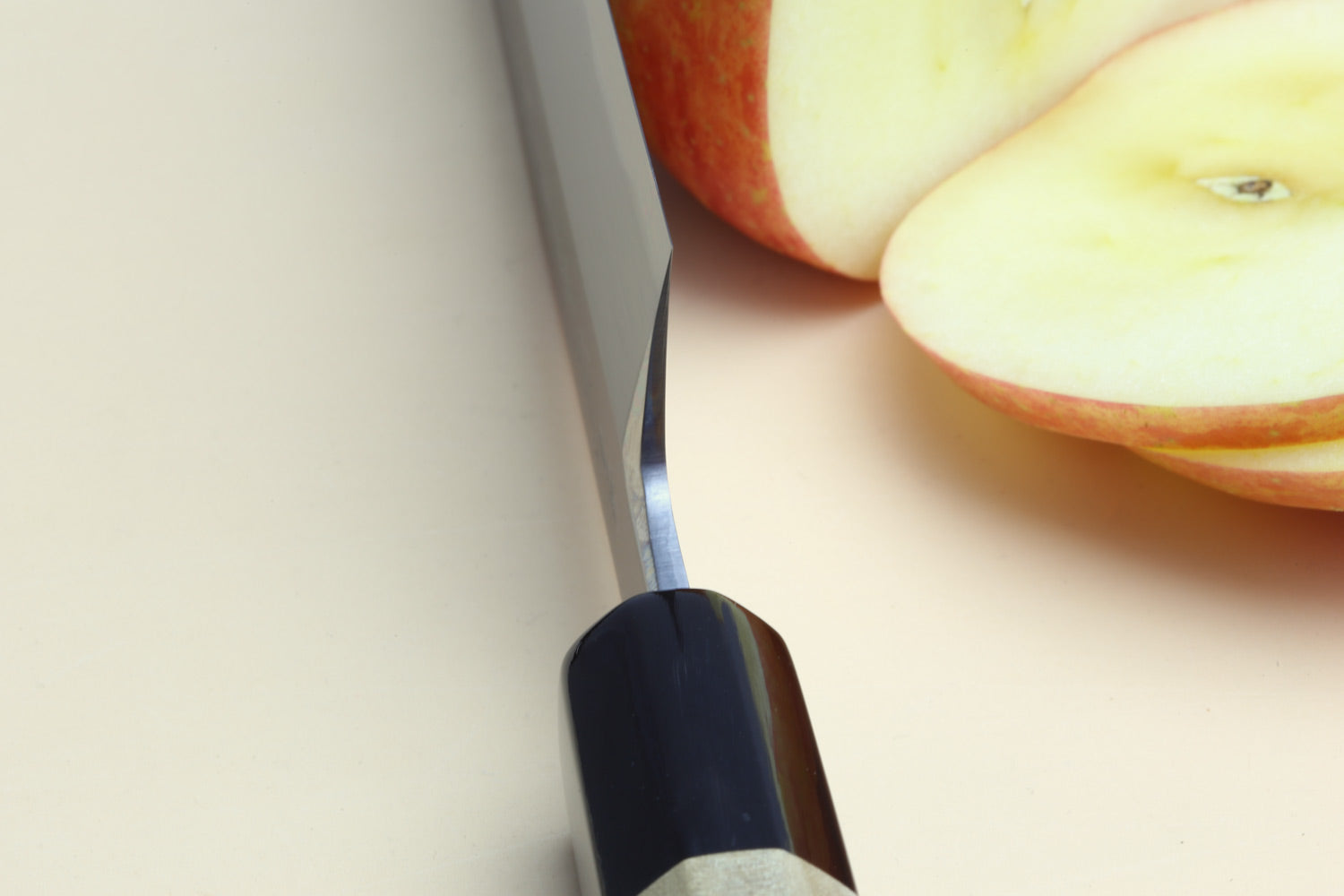 Japanese chef knife profile with dark bolster and light wooden handle