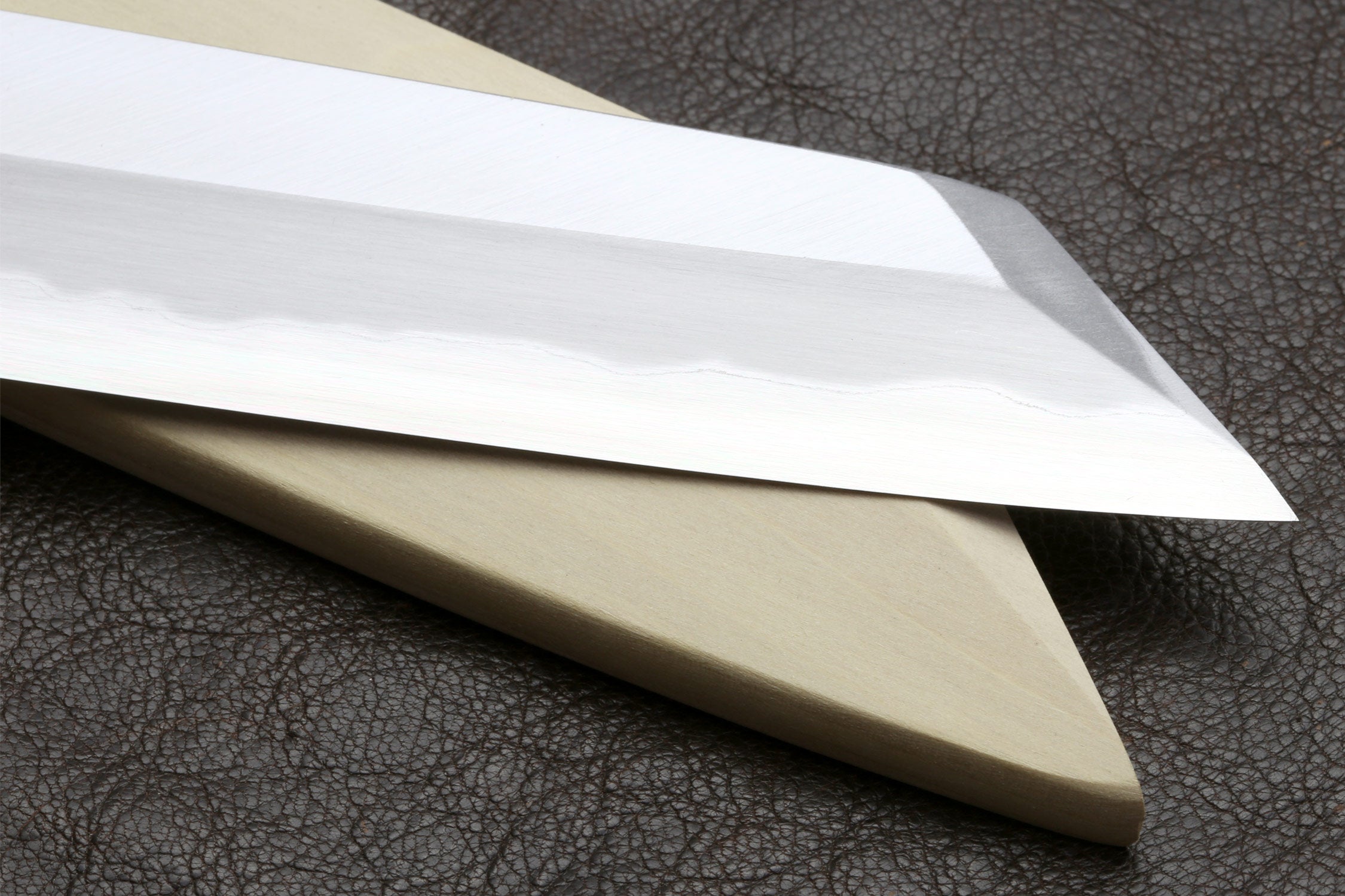 Japanese chef knife blade and handle shown in profile on dark leather