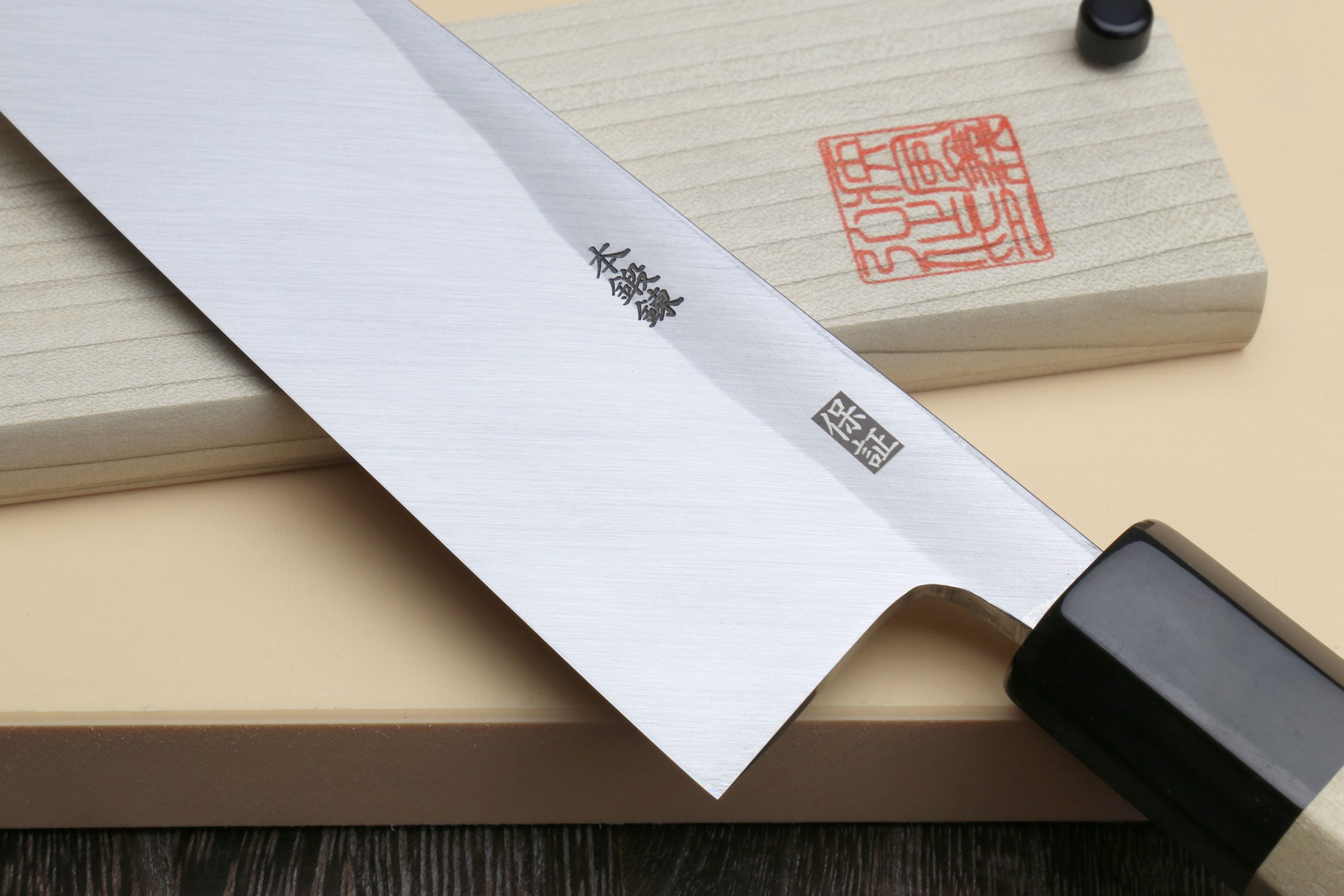 Japanese sashimi knife with smooth silver blade and black collar over light handle