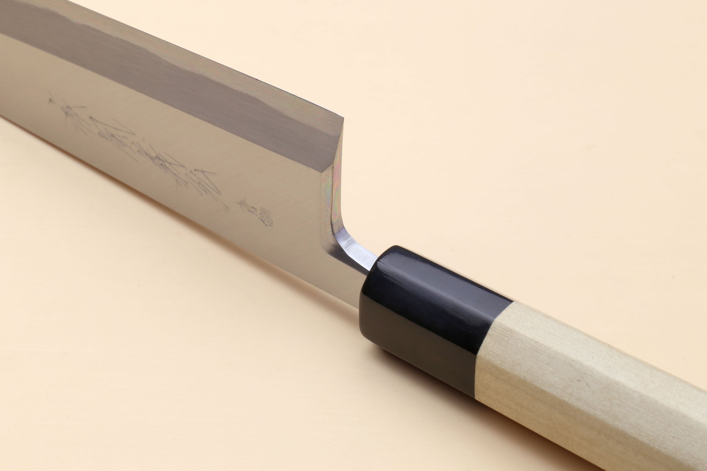 Japanese chef knife side view with black collar, light handle, and shiny silver blade