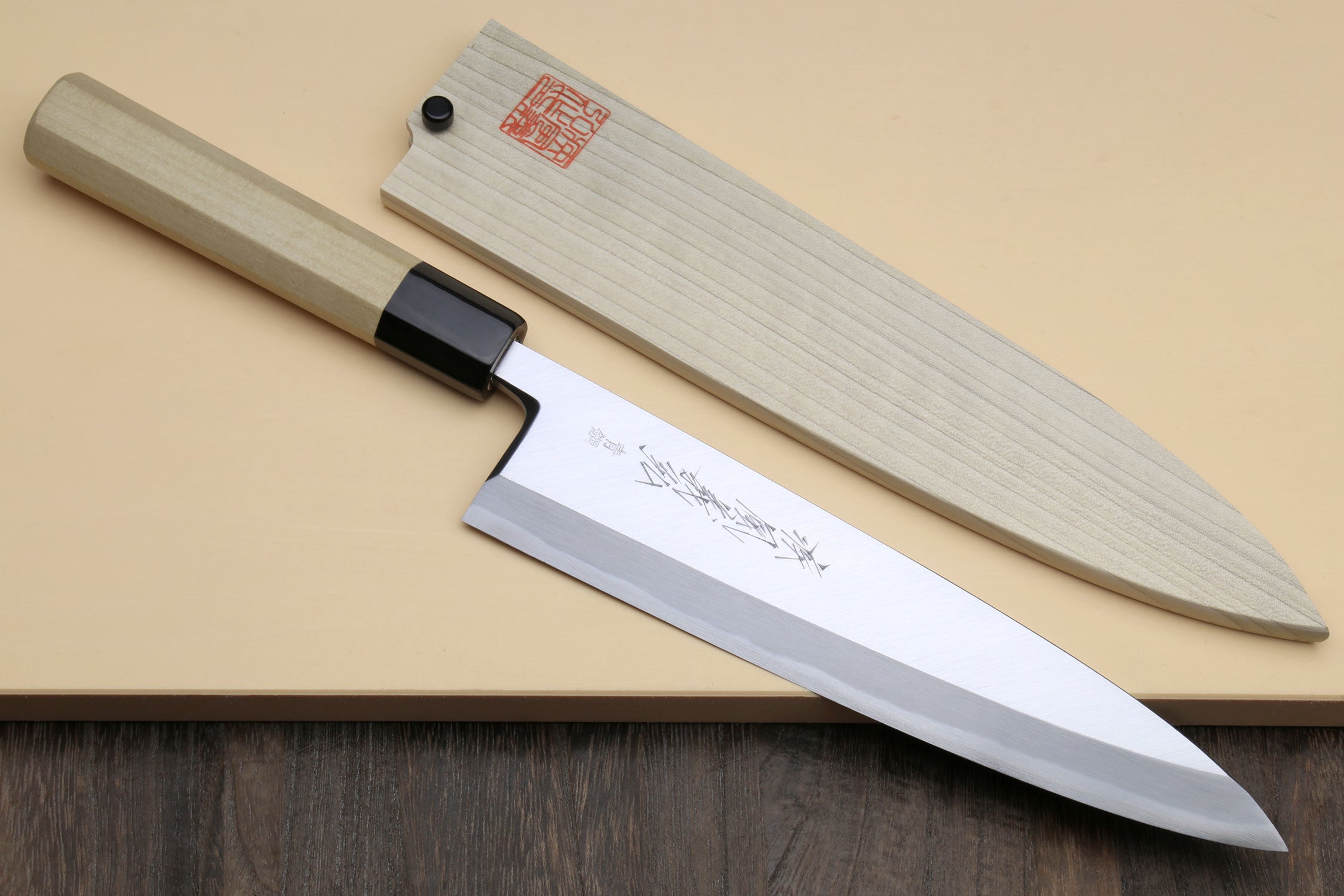 Japanese filet sushi knife with light wood handle and dark blue-steel blade, black collar