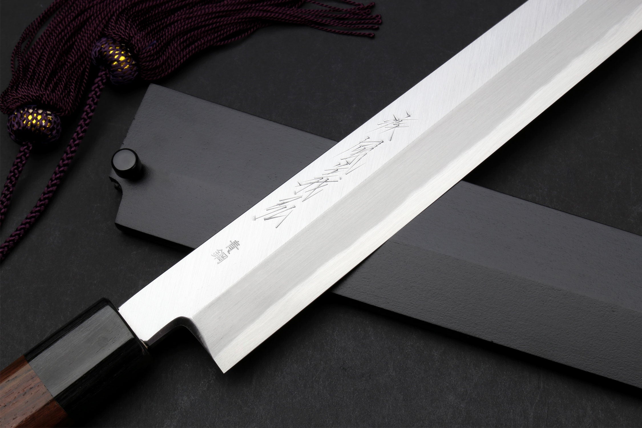 Japanese yanagi knife with engraved blade, rosewood handle, and sheath with cord