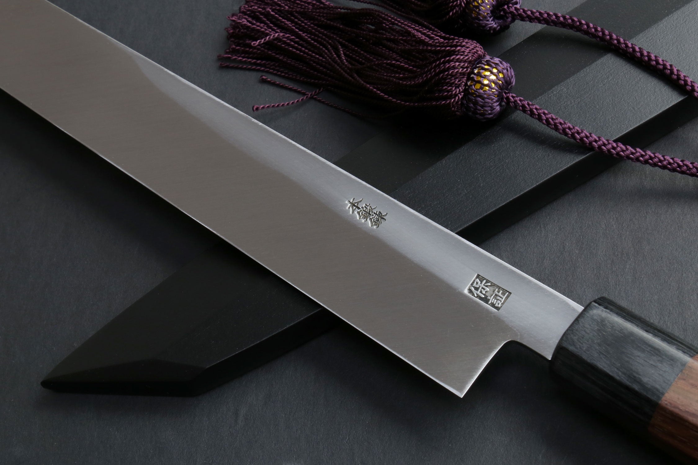 Japanese yanagi knife close-up: steel blade with logo and rosewood handle