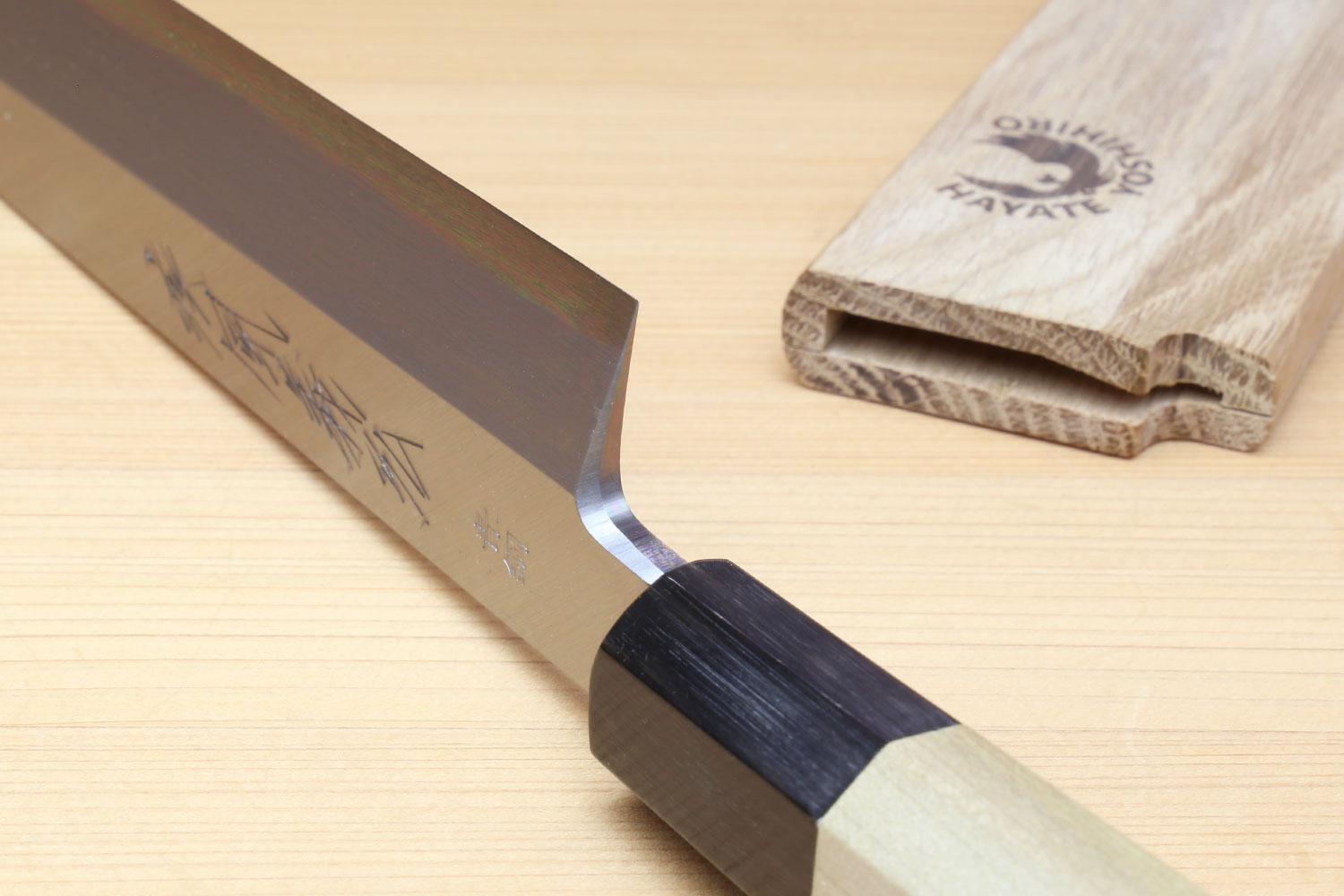 Japanese sashimi knife beside blade edge, silver steel with black bolster and magnolia handle