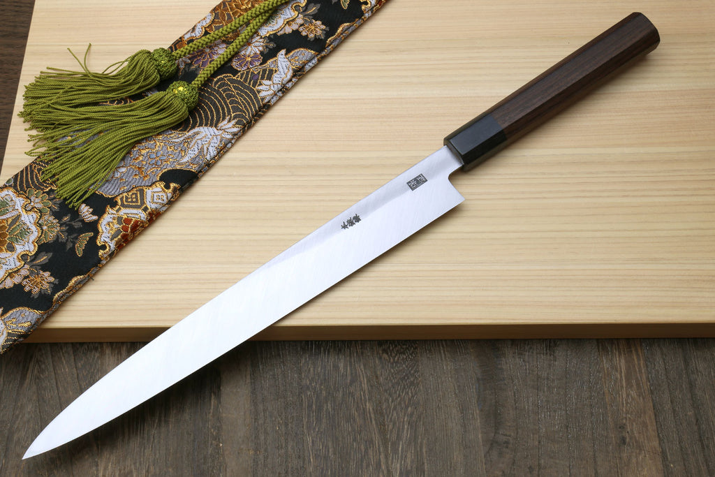 Sashimi knife with rosewood handle and slim silver blade on a wooden board