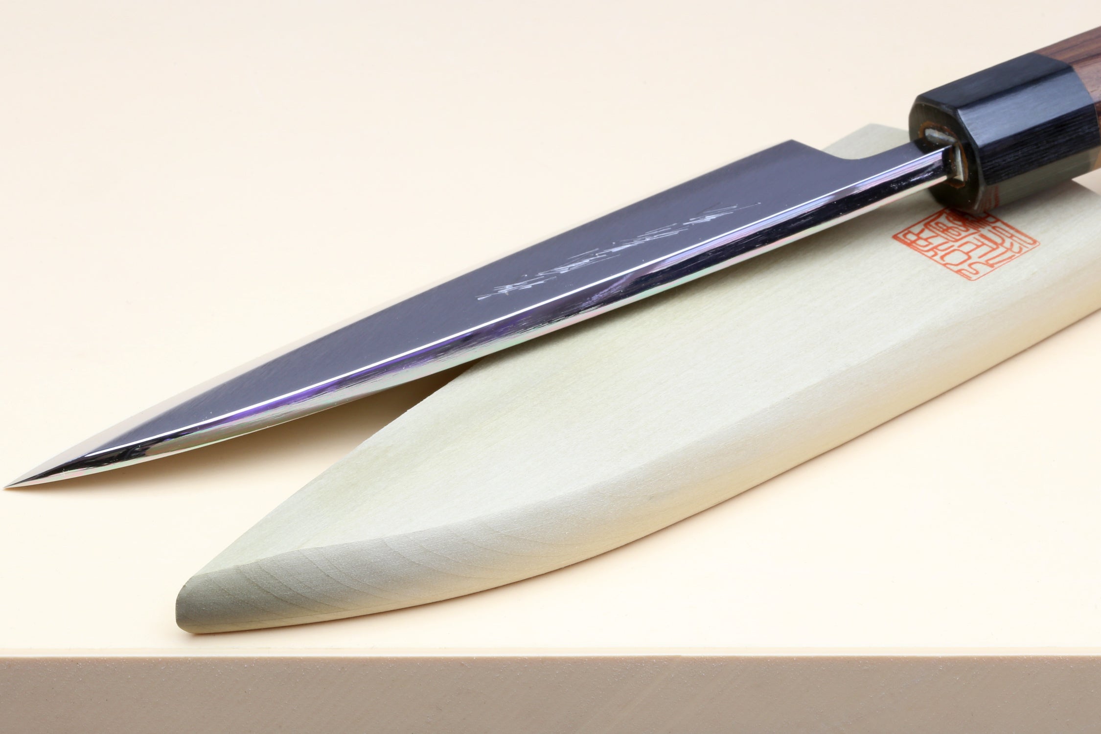 Deba knife edge and blade close-up with white steel and rosewood handle, dark bolster