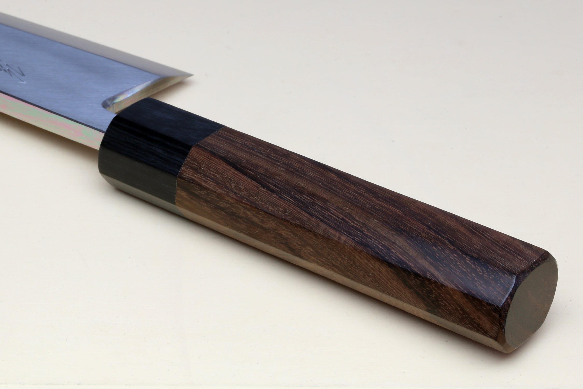 Deba knife handle close-up: dark bolster and brown rosewood scales on a white blade