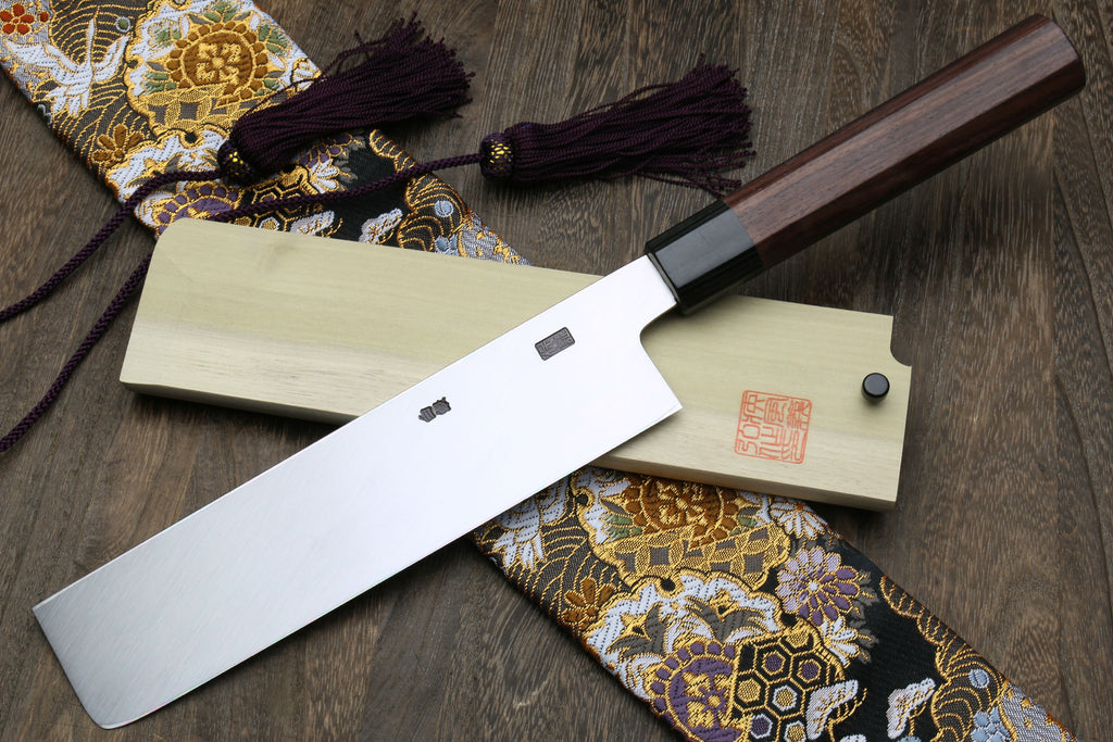 Japanese chef knife with dark handle and light sheath, slanted view