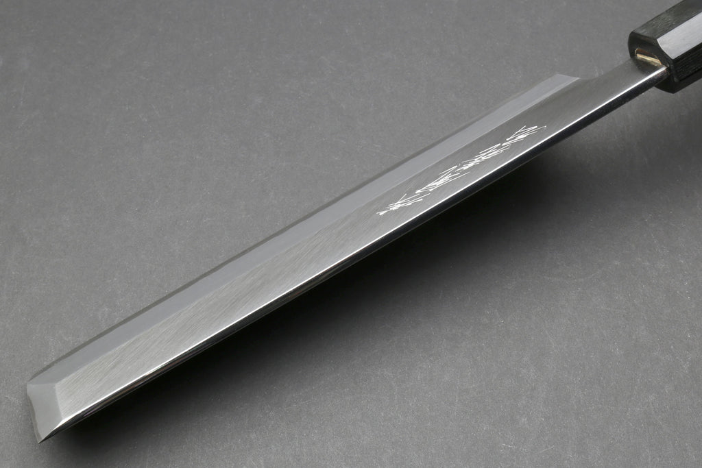 Japanese chef knife blade close-up with polished edge and dark bolster