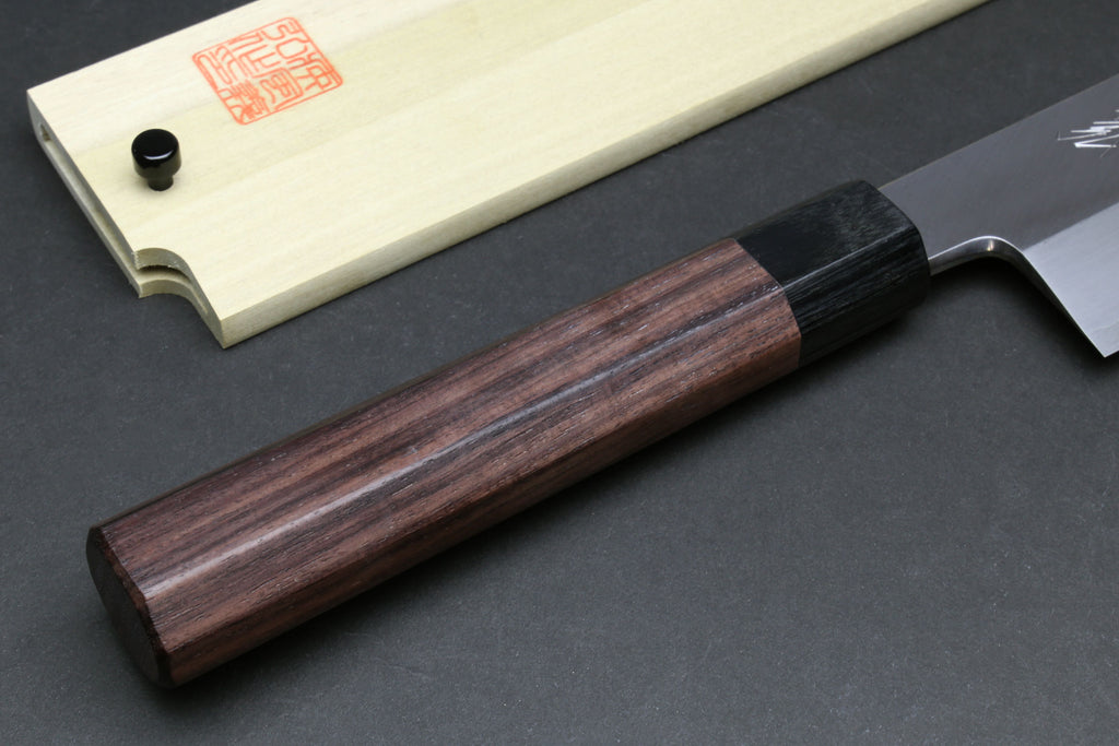 Japanese chef knife wooden handle close-up with dark bolster and pale saya