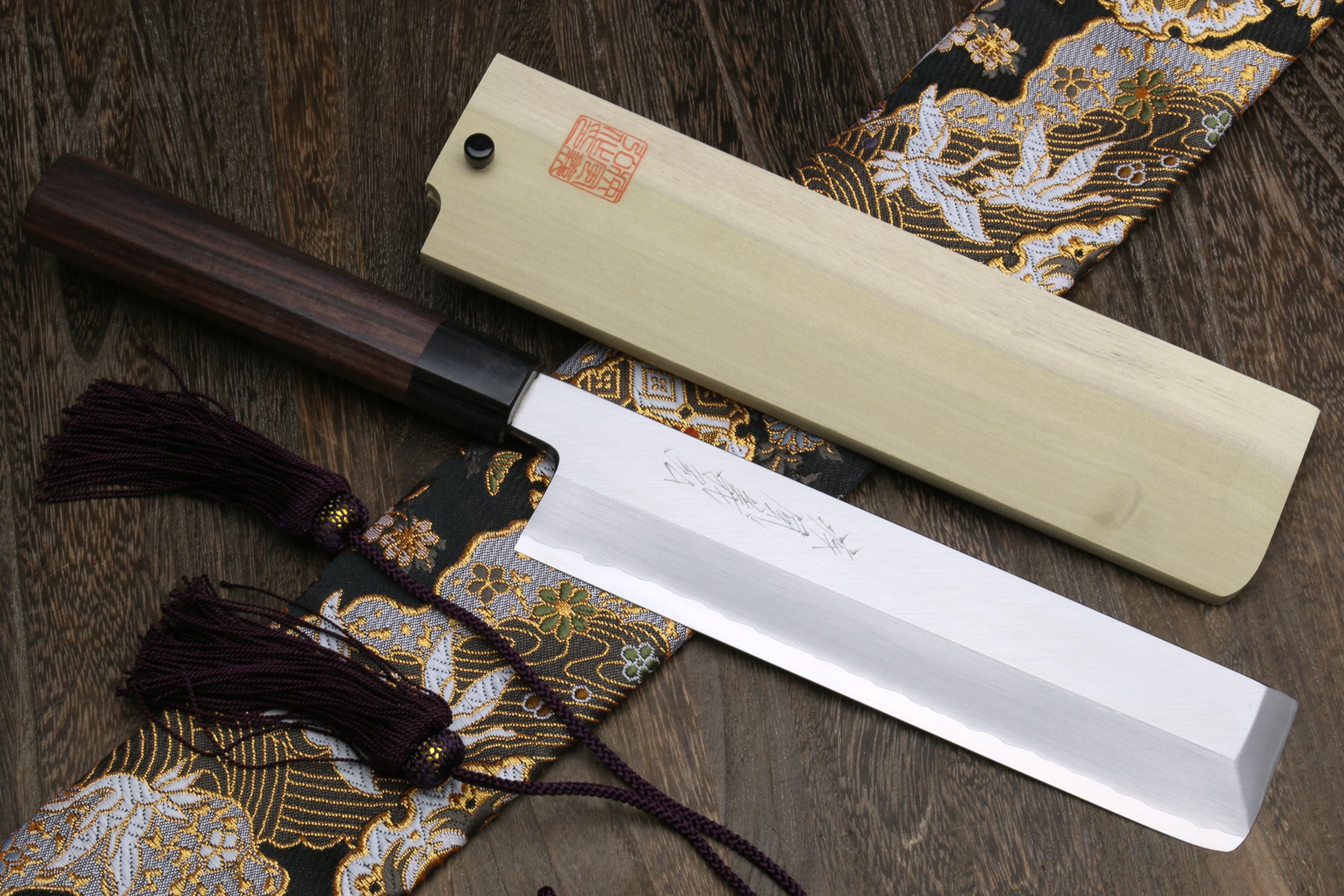 Japanese chef knife with dark wooden handle and light wooden sheath