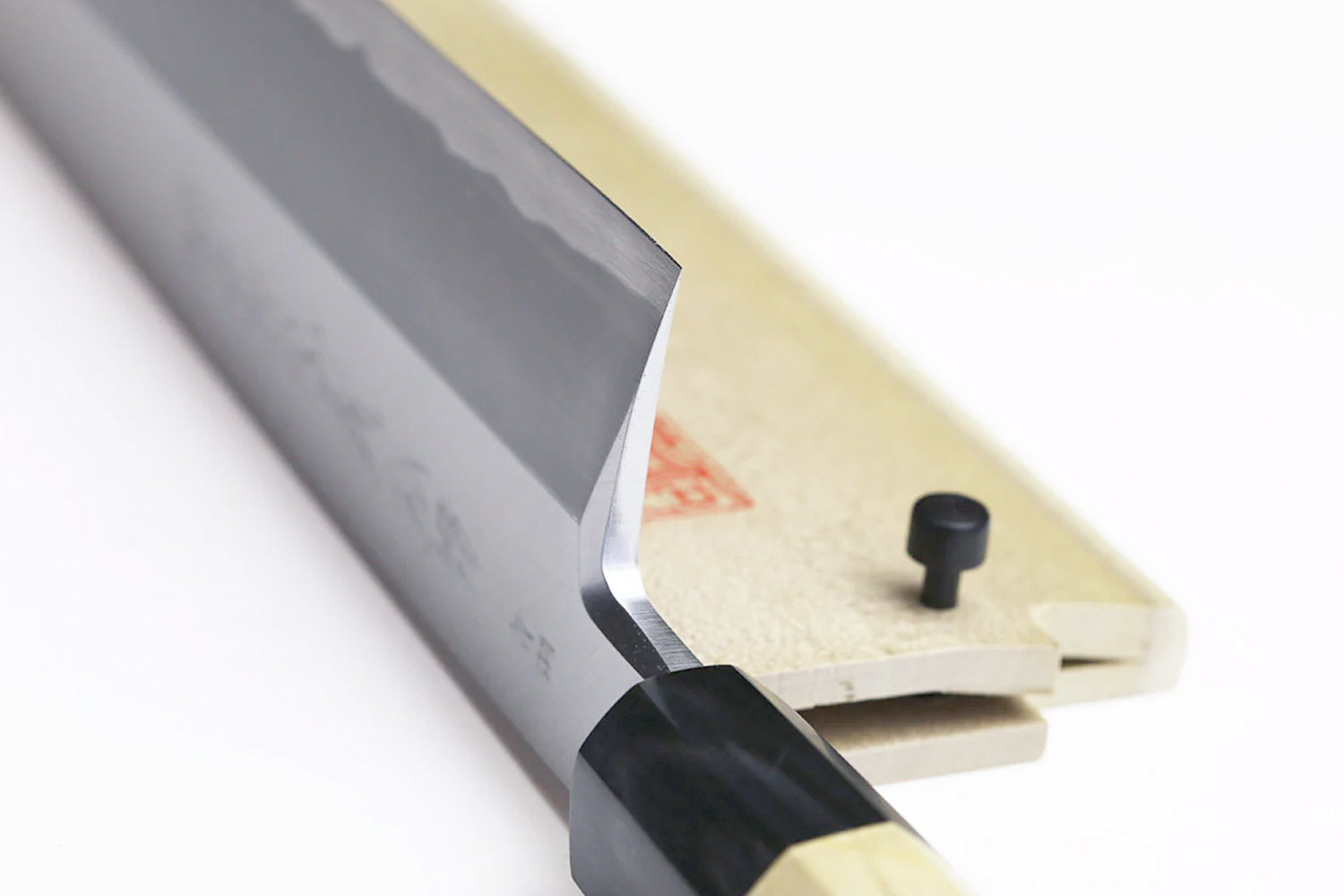 Japanese eel bone slicer knife blade close-up with black collar and light wood support