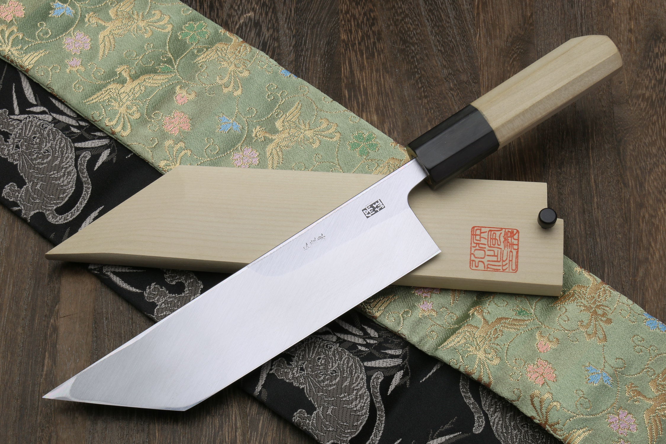 Eel filet knife with sheath and long blade on dark and green patterned fabric