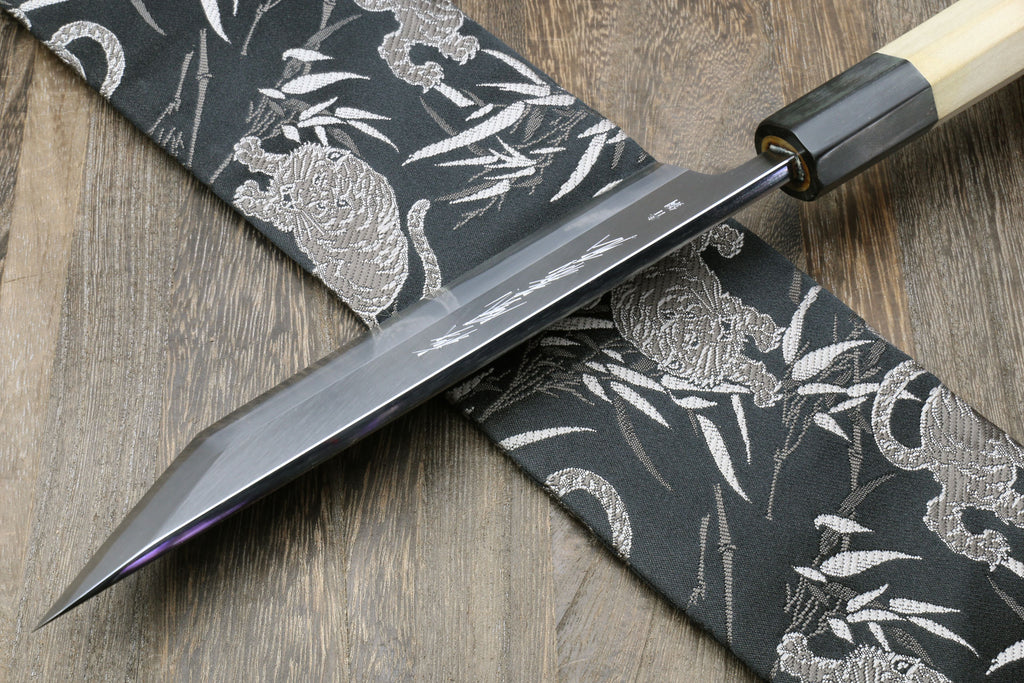 Eel filet knife with pointed blade crossing on dark patterned fabric