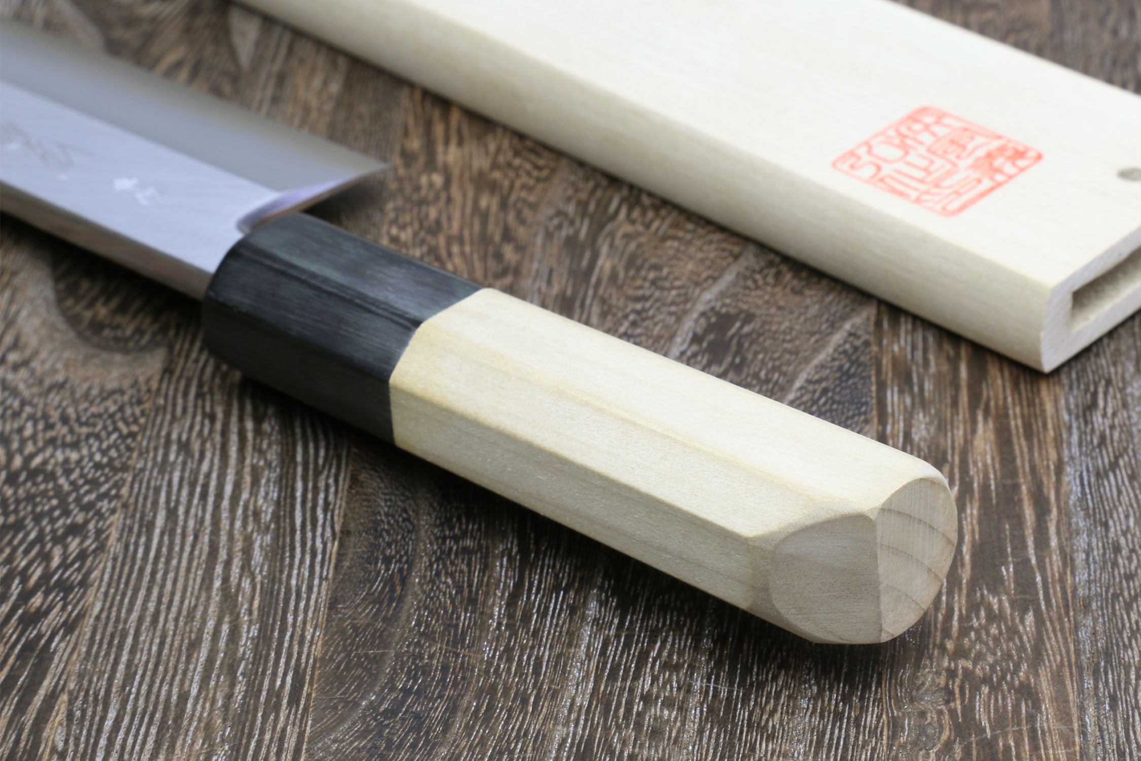 Eel filet knife with pale handle and black bolster, close-up view