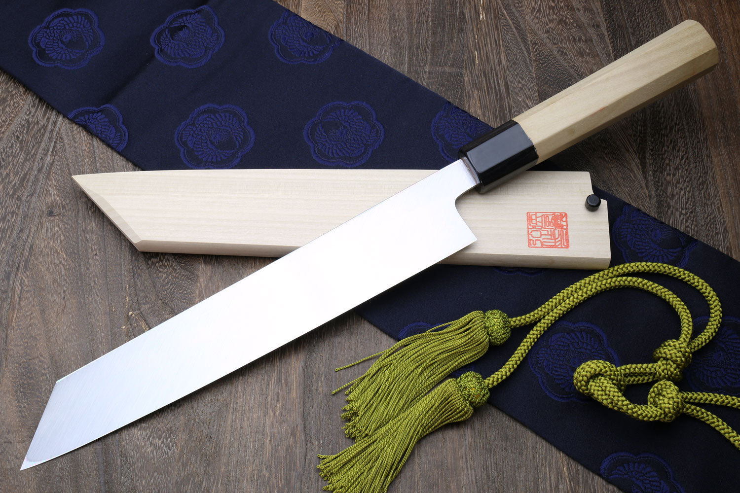 Multipurpose Japanese chef knife with white steel blade, magnolia handle, green tassel cord.