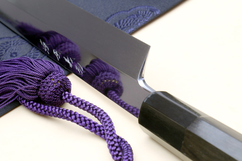 Yanagi sushi knife blade detail with purple cord ties and dark handle