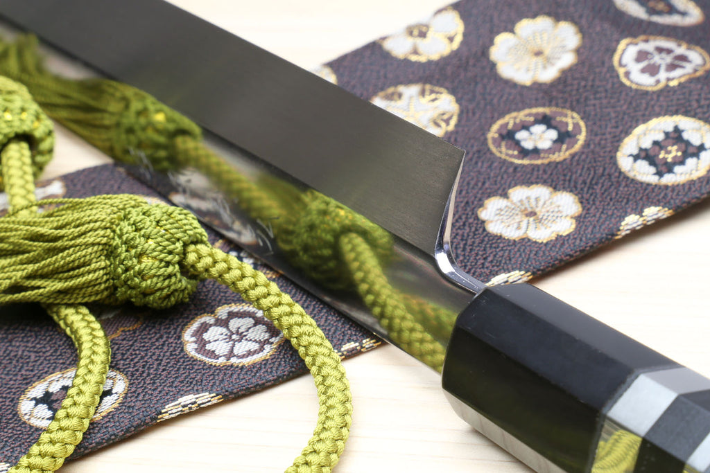 Yanagi sushi knife with mirror-finished silver blade, dark handle, and green cord tassel