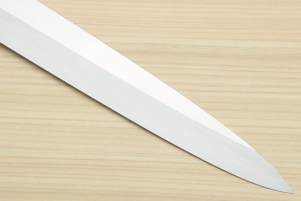 Yanagi sushi knife with mirror-finished silver blade on light wood surface