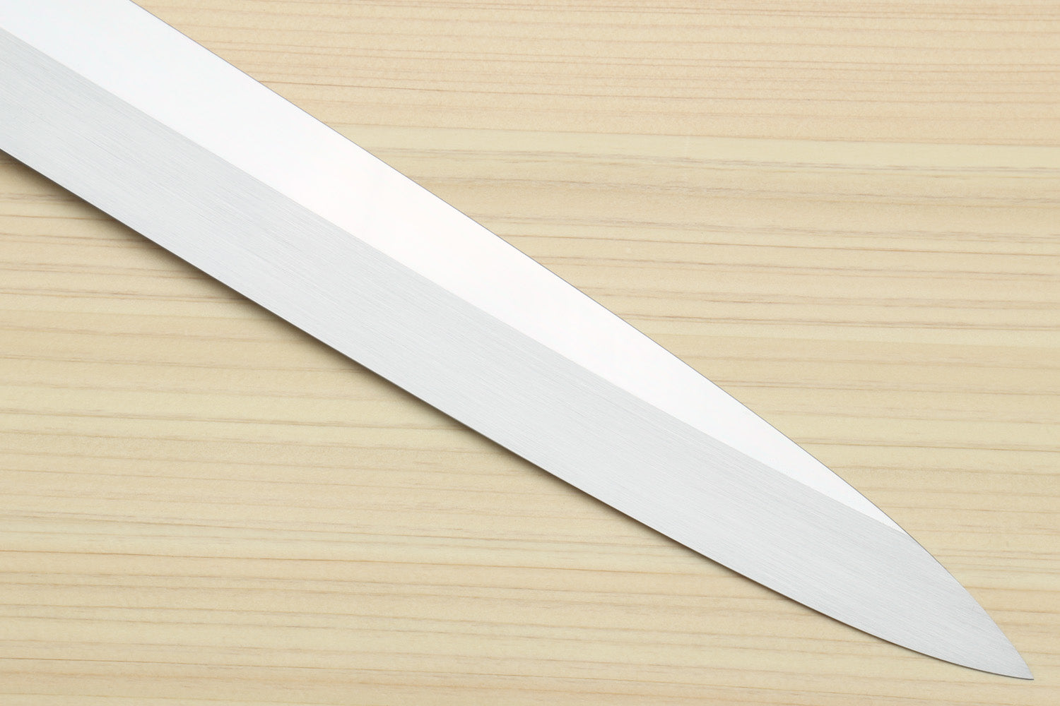 Yanagi sushi knife with mirror-finished silver blade on light wood surface