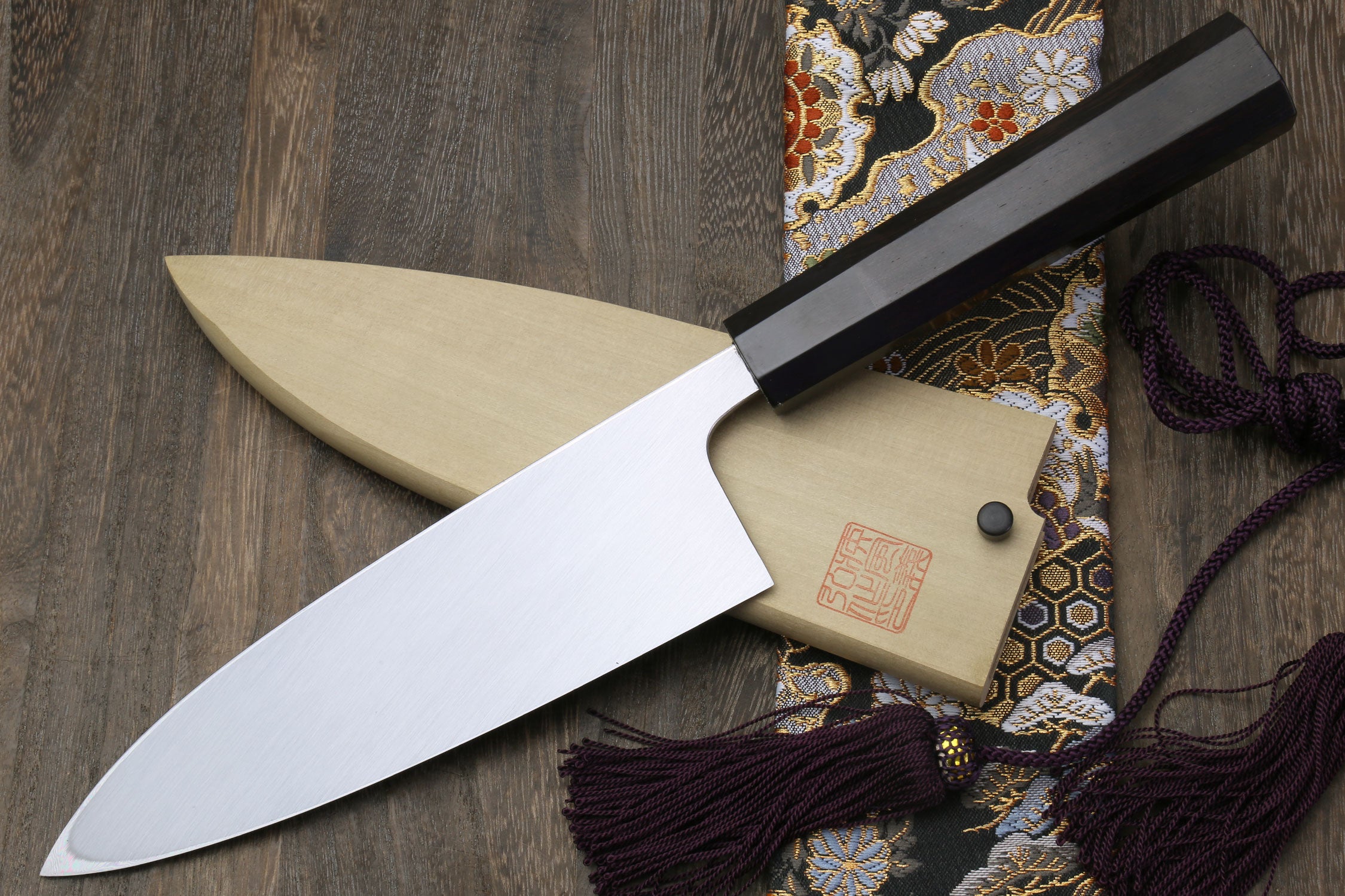 Mirror-finished deba sushi fillet knife with dark handle and light wooden saya