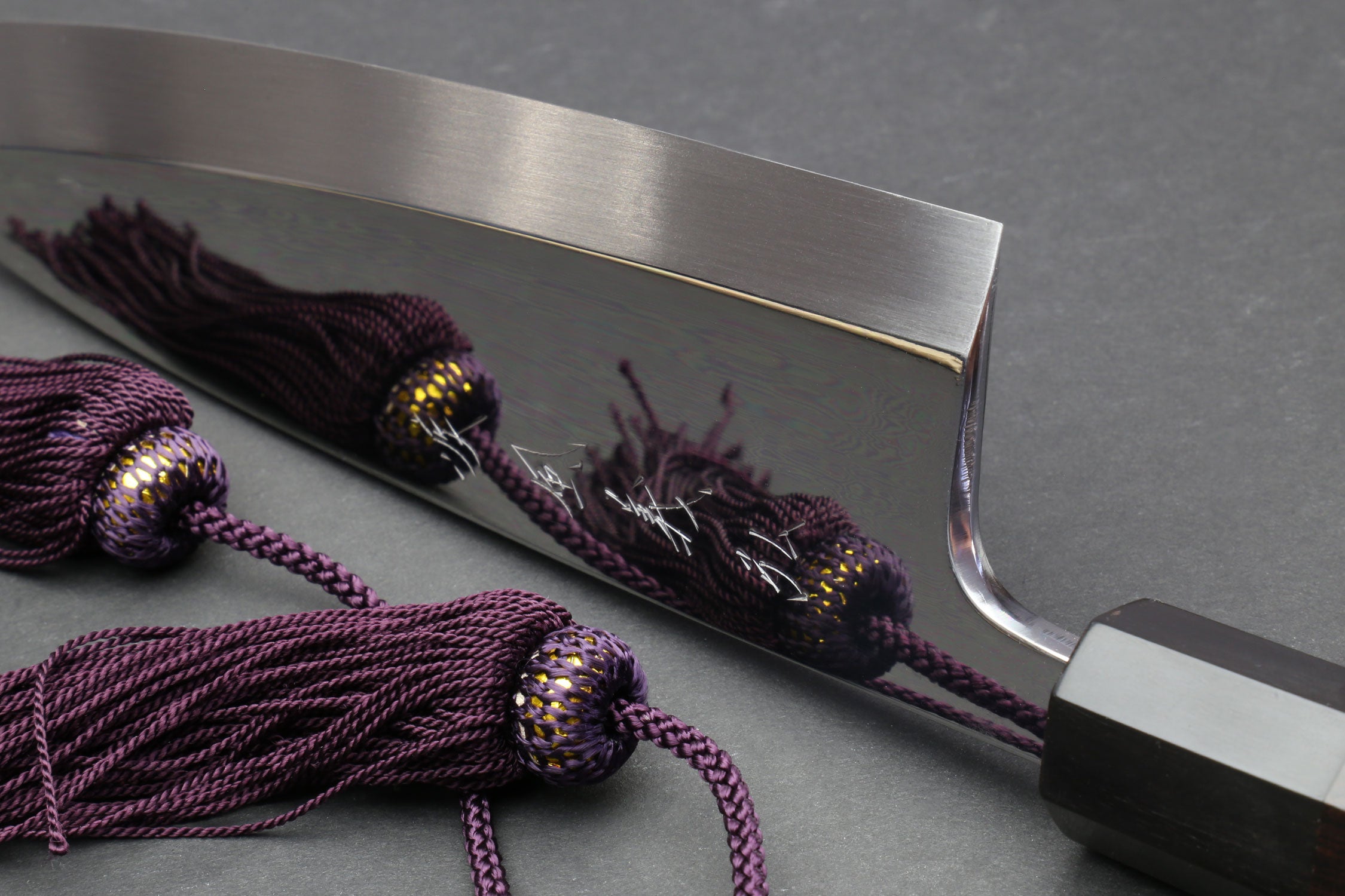 Mirror-finished deba sushi fillet knife with dark handle and purple braided cords