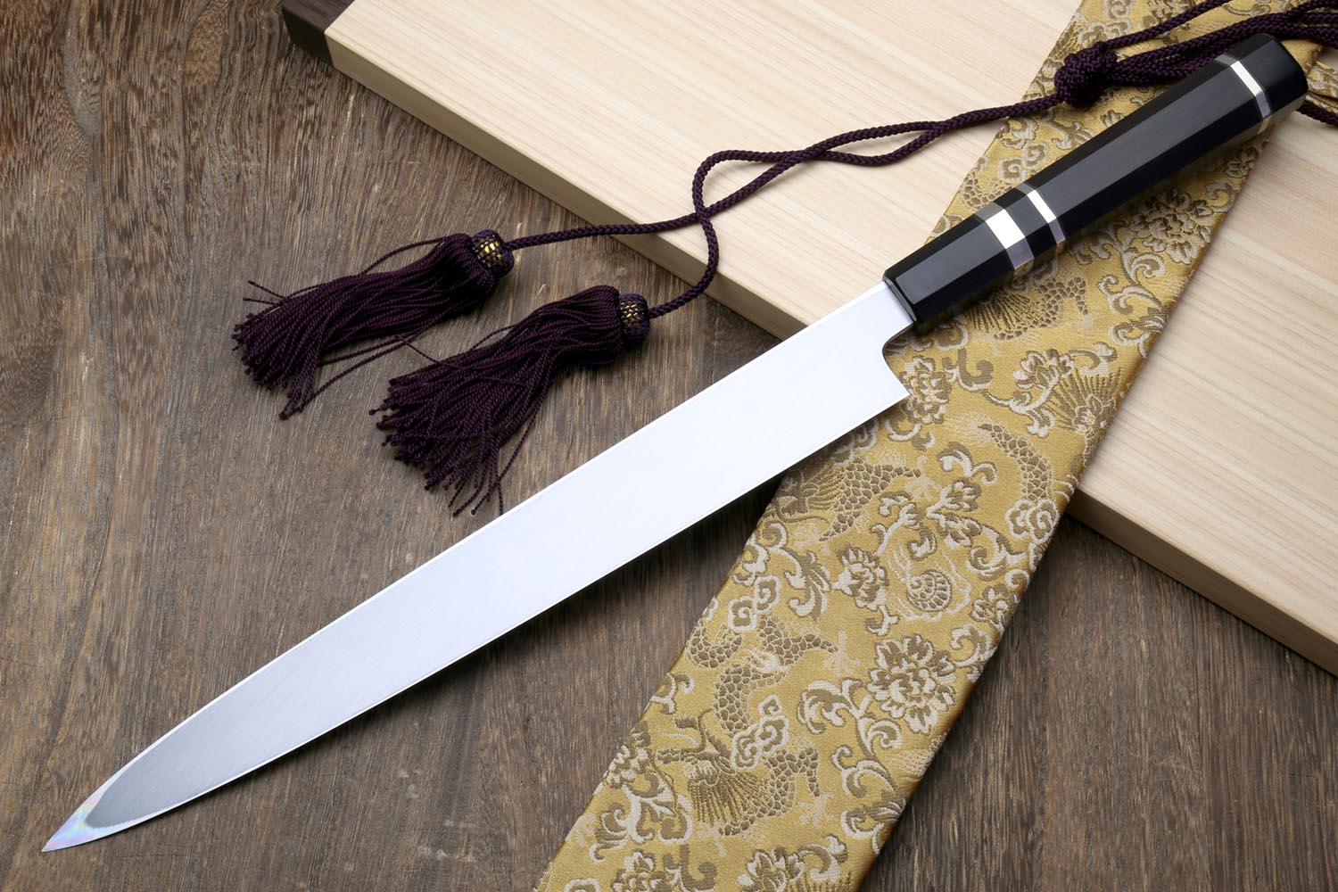 Japanese yanagiba sushi knife with long mirror-finished blade and black cord tassel handle