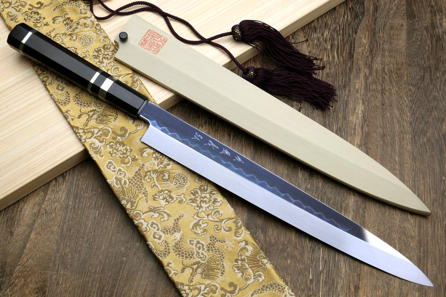 Japanese yanagiba sushi knife with mirror-finished white blade and black handle with silver bands