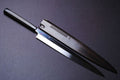 Mirror-finished steel Japanese knife with dark handle, slim blade