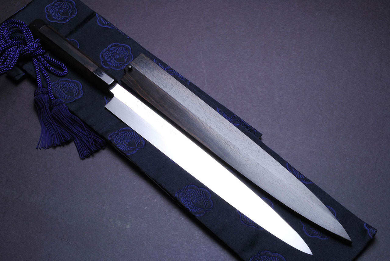 Mirror-finished steel Japanese knife with dark handle and blue storage cloth
