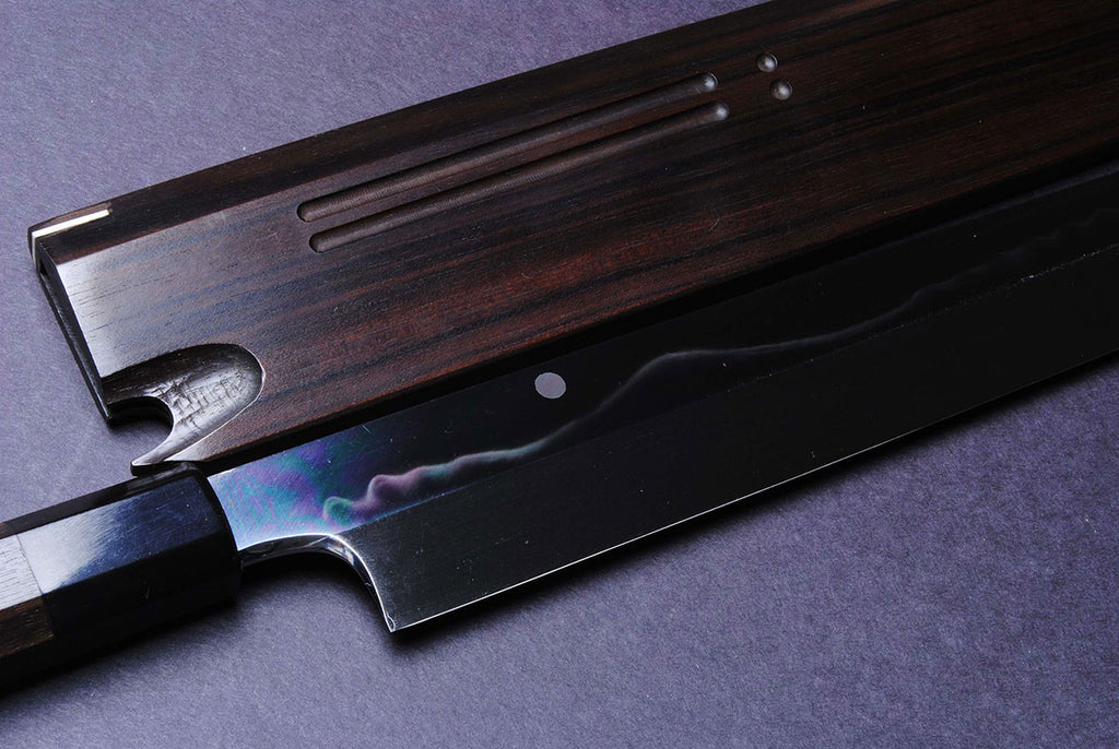 Japanese kitchen knife with dark handle, mirror blade edge close-up