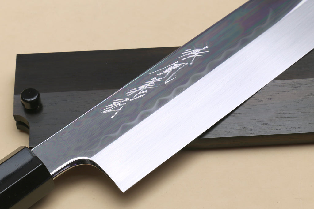 Japanese vegetable knife blade close-up with black handle and decorative markings