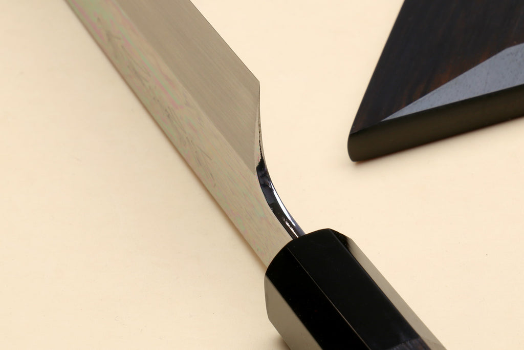 Japanese vegetable knife showing blade heel with black handle and saya cover