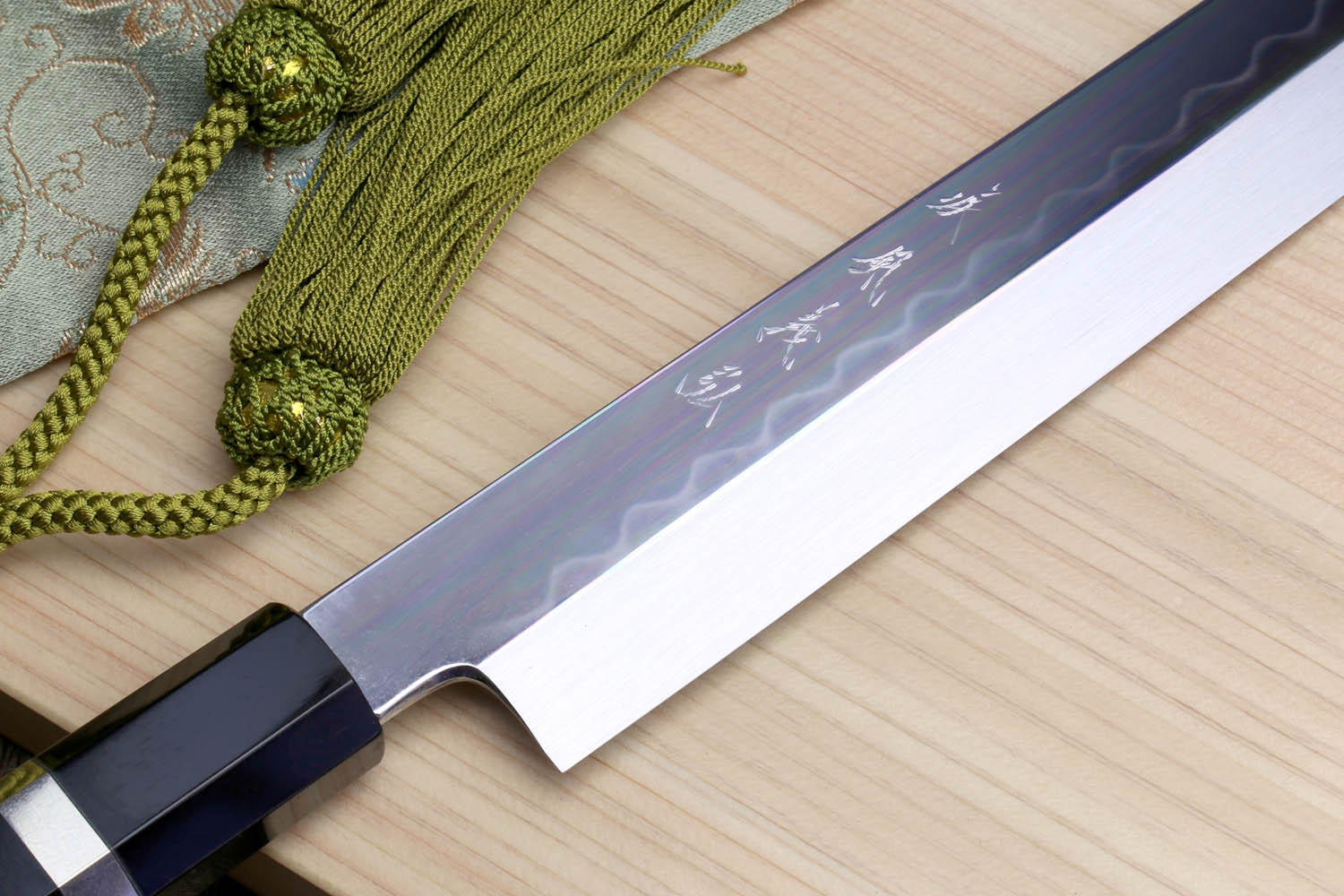 Japanese sushi knife with patterned blade surface and black handle with checkered ring