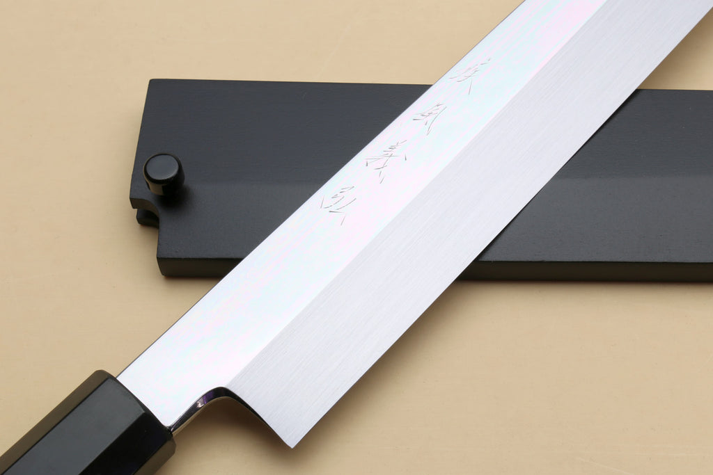 Yanagi knife blade with mirror steel finish and dark guard, showing subtle engravings.
