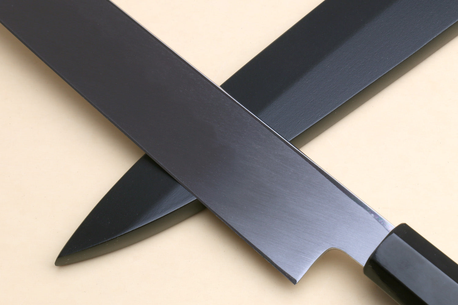 Yanagi knife at an angle with long mirror-finished blade and dark handle.