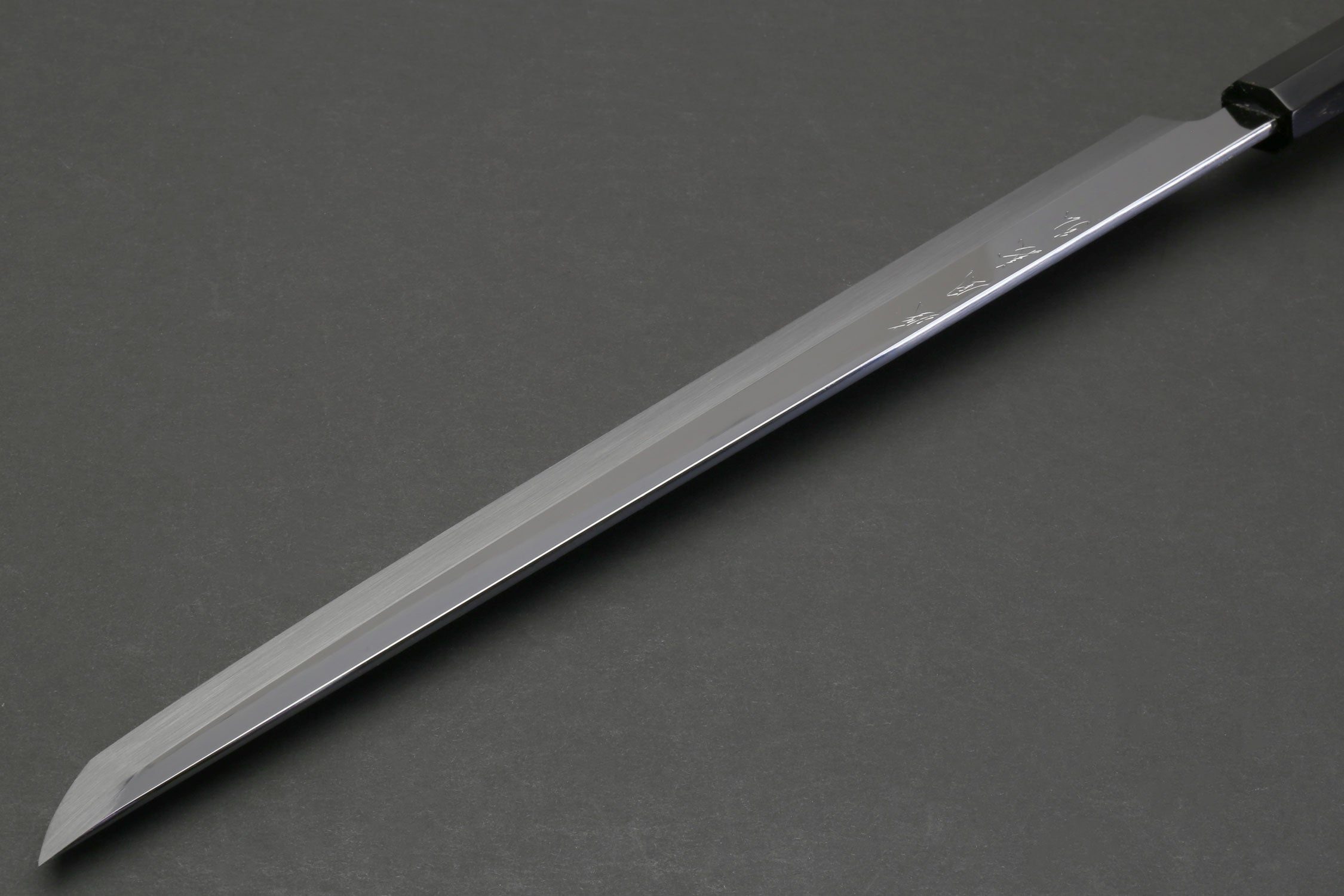 Japanese sushi knife side view with mirror-finished blade and dark ebony handle.