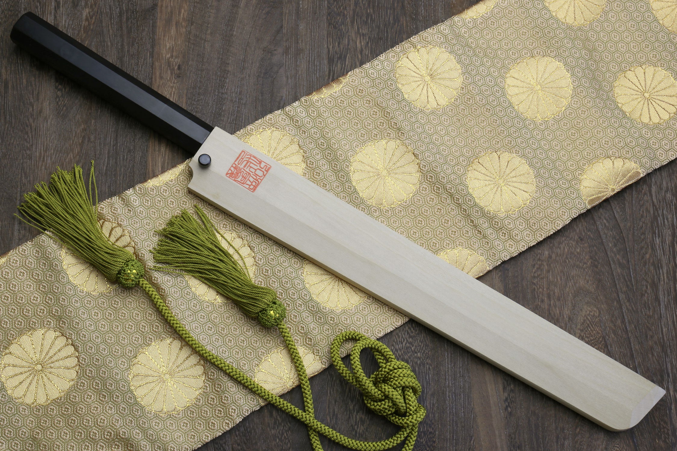Sushi chef knife with mirror-finished blade, dark ebony handle, and green tassel cord.