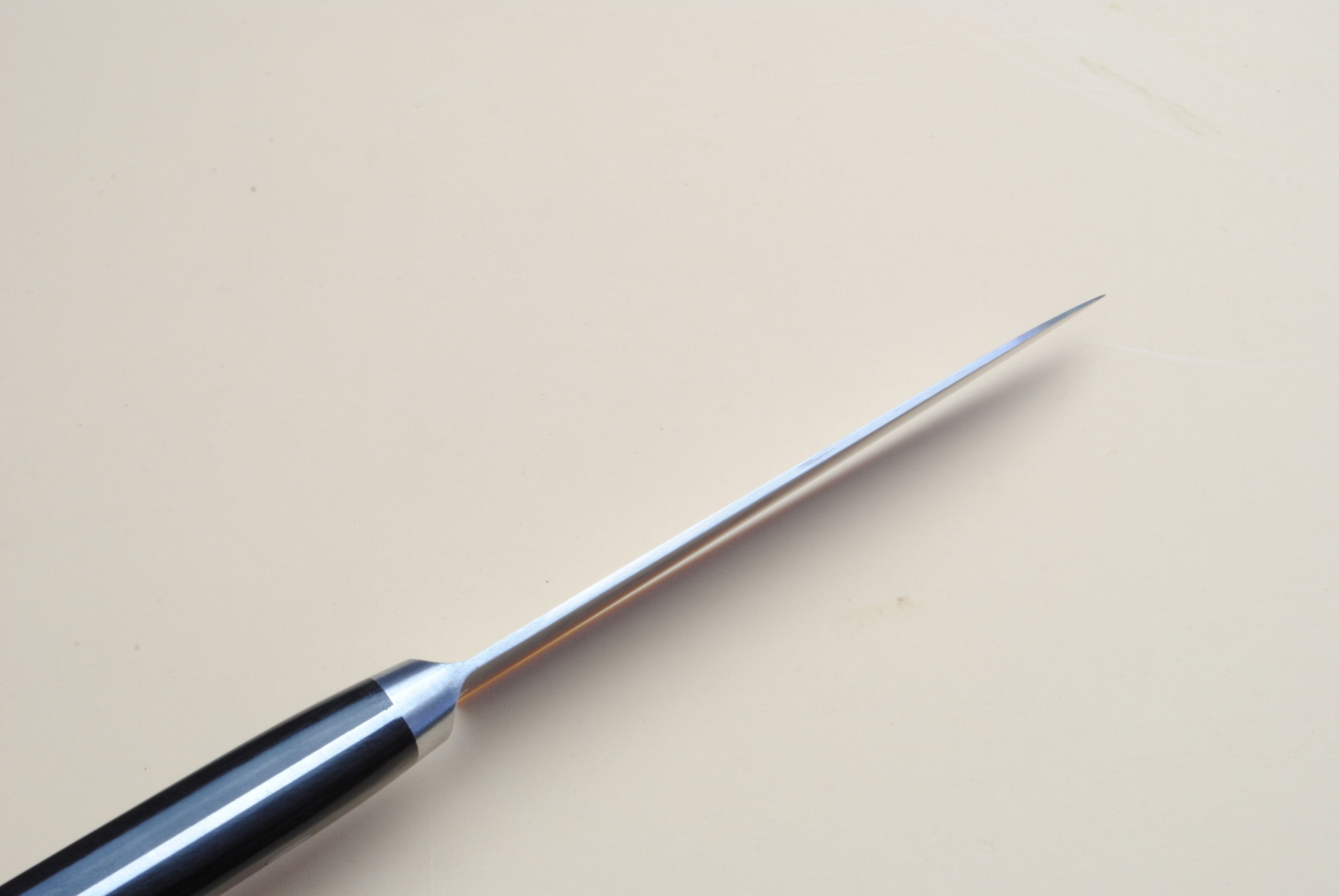 Petty knife tip with dark handle and polished steel blade