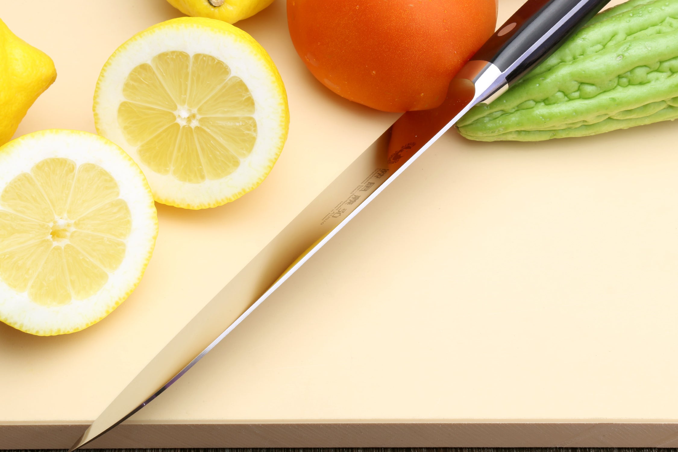 Santoku chef’s knife angled on board with stainless steel blade and black handle