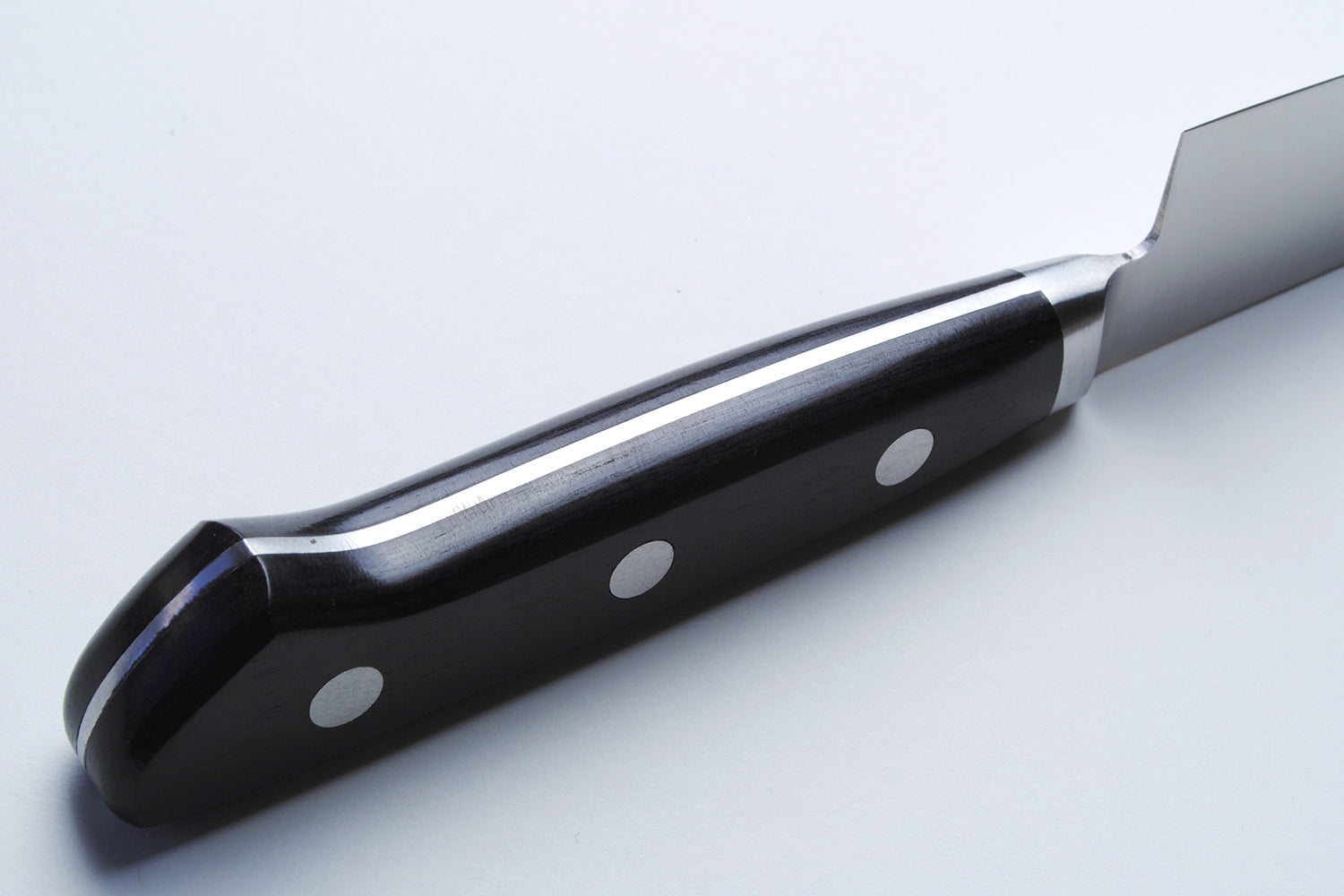 Santoku chef’s knife handle close-up with black scales and silver rivets on dark bolster