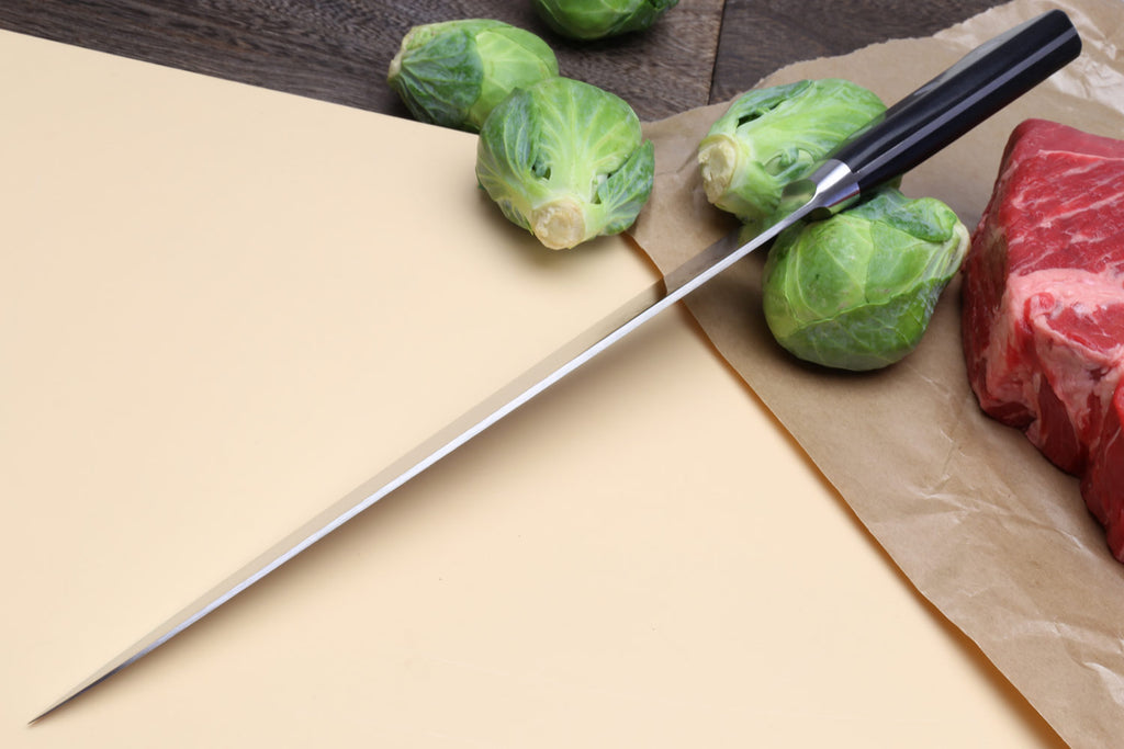 Sujihiki slicer chef knife with long thin blade and dark handle on cutting board