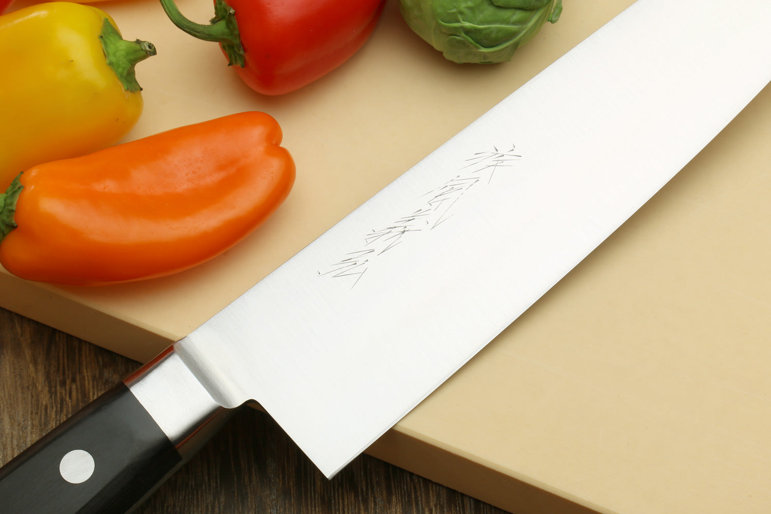 Double-edged deba fillet knife blade and bolster with dark handle, close-up