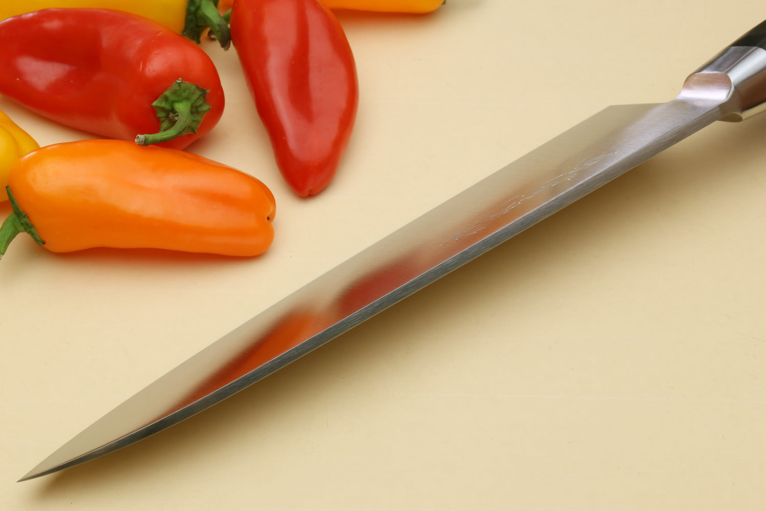 Double-edged deba fillet knife with pointed silver blade and dark handle, side view