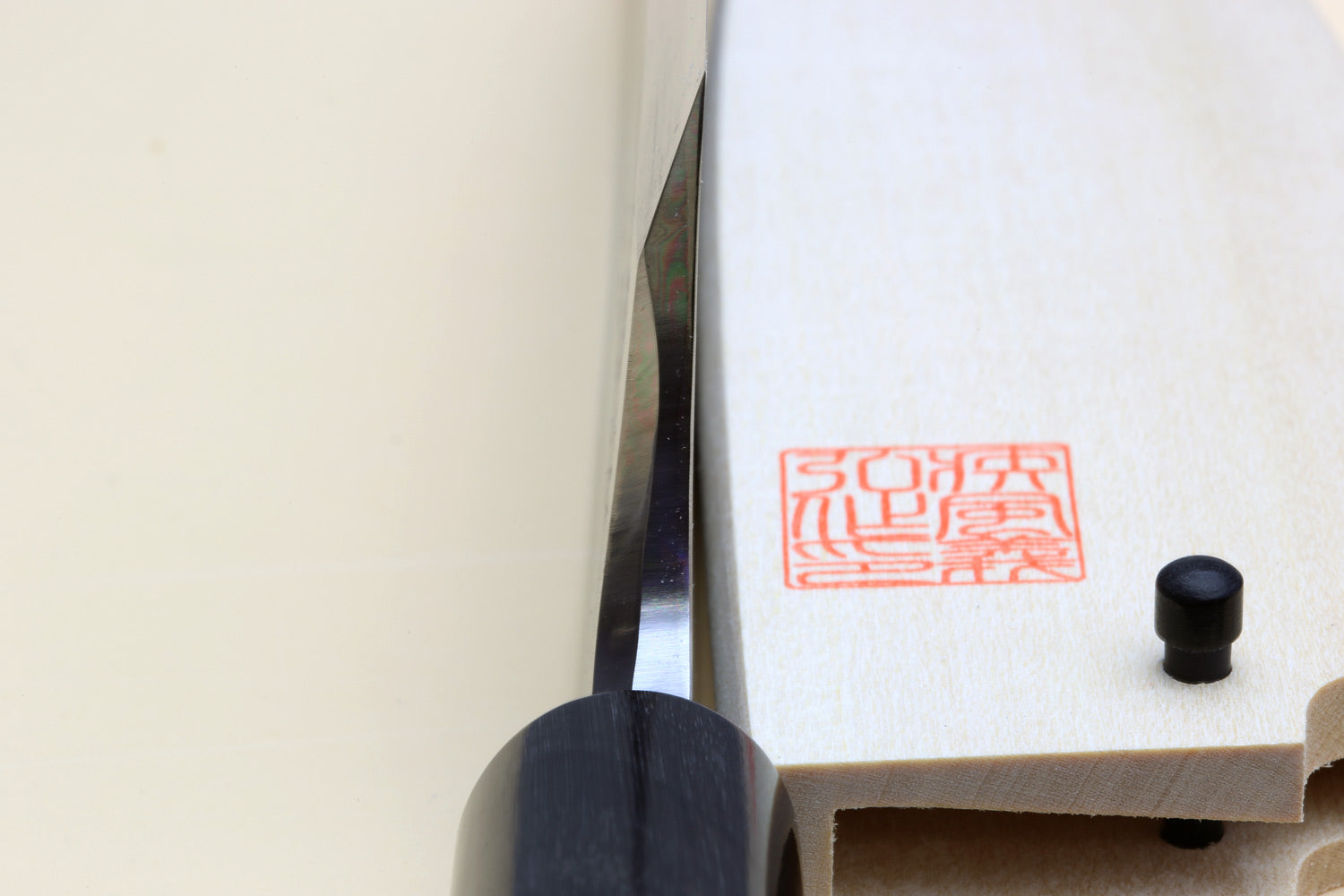 Deba knife close-up: white blade edge, black ferrule, light magnolia handle